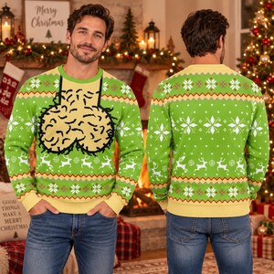 May include: A bright green long-sleeve knit jumper featuring a graphic of a tan, textured, rounded shape with black outlines on the front. The jumper includes a repeating pattern of white snowflakes, reindeer, and geometric zig-zag lines in red and yellow.