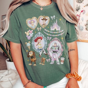 May include: Green t-shirt with a colourful graphic design featuring characters from the animated film Toy Story. The design includes portraits of Woody, Buzz Lightyear, Jessie, and others, with the text "Toy... Infinity... and Beyond".