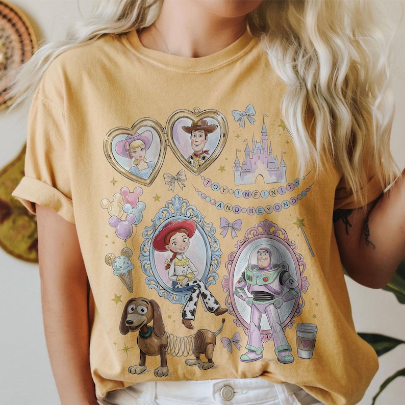 May include: Mustard yellow t-shirt with illustrations of Toy Story characters. The design includes portraits of Woody, Jessie, Buzz Lightyear, and others, along with the text "TO INFINITY AND BEYOND".