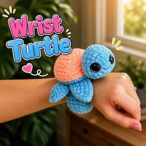 May include: A blue and peach crochet turtle wristband with large black eyes and a smiling face. The text "Wrist Turtle" is displayed in pink and blue above the turtle. The turtle is worn on a wrist.