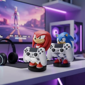 Puede incluir: Dos figuras de personajes, Knuckles y Sonic, cada uno sosteniendo un mando de juego blanco. Knuckles es rojo con la cara amarilla, y Sonic es azul. Ambos están sobre bases negras, con un monitor de ordenador y auriculares en el fondo.