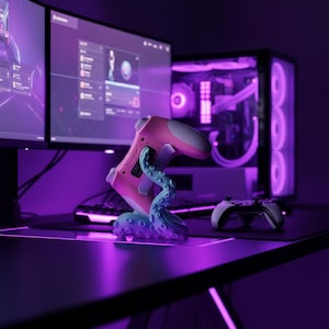 May include: A pink and white gaming controller stand with a blue tentacle design. The stand is on a desk with a computer and other gaming accessories. The scene is illuminated with purple lighting.