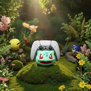 Puede incluir: Un mando blanco de PlayStation 5 descansa sobre una figura verde de Bulbasaur, con un Pikachu amarillo y una Poké Ball azul al fondo. La escena está ambientada en un entorno verde exuberante con flores y musgo.