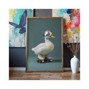 May include: A framed art print featuring a white duck wearing a geometric helmet and roller skates. The duck has a yellow beak and is set against a teal background. Other artwork and a vase are visible in the background.