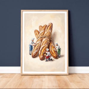 Könnte beinhalten: Gerahmter Kunstdruck mit einem Stillleben aus mehreren mit Bindfaden zusammengebundenen Baguettes. Miniaturköche sind um das Brot herum dargestellt, was einen skurrilen Touch verleiht. Das Kunstwerk ist vor einem neutralen Hintergrund in hellem Holz gerahmt.