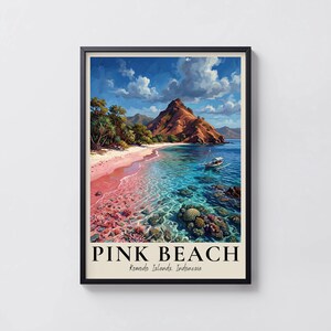 May include: A framed print of Pink Beach in Komodo Islands, Indonesia. The artwork shows a beach scene with pink sand, turquoise water, and a mountain. The sky is blue with white clouds. The words "PINK BEACH" are printed at the bottom of the image.