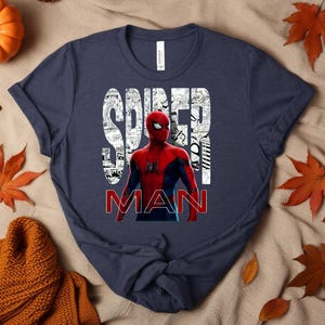 Peut inclure: Un t-shirt bleu marine &agrave; manches courtes avec un graphisme du personnage Spider-Man en costume rouge et bleu. Le mot SPIDER est imprim&eacute; en blanc avec un motif de planches de bande dessin&eacute;e, et le mot MAN est en lettres rouges grasses.