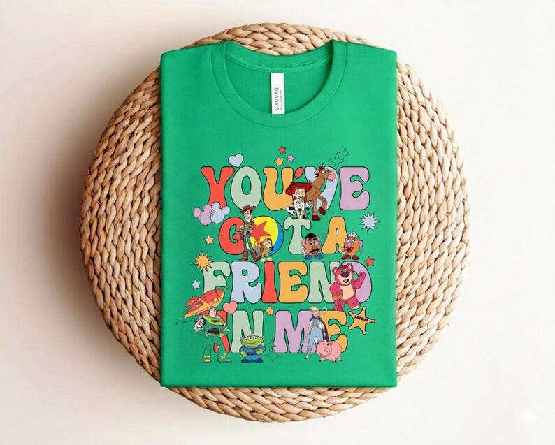 May include: A green t-shirt with the text "You've Got a Friend in Me" in a retro font, accompanied by cartoon characters. The shirt is displayed on a woven, circular surface. The t-shirt is a vibrant and playful design.