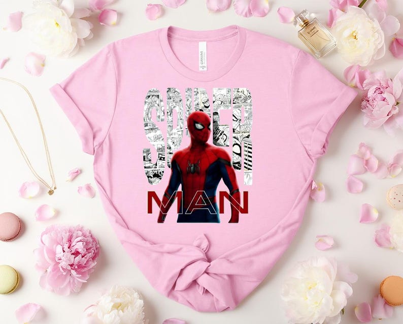 Peut inclure: Un t-shirt rose clair &agrave; manches courtes avec un graphisme du personnage Spider-Man en costume rouge et bleu. Le mot SPIDER est rempli de panneaux de bande dessin&eacute;e en noir et blanc, et le mot MAN est imprim&eacute; en lettres rouges grasses.