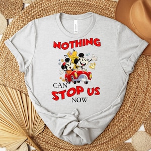 Puede incluir: Camiseta gris claro con una imagen de dibujos animados de Mickey y Minnie Mouse en un coche rojo, con el texto "NOTHING CAN STOP US NOW" en rojo. La camiseta es de material suave y tiene mangas cortas.