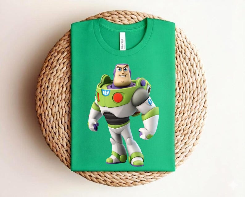May include: A green t-shirt featuring a colorful graphic of Buzz Lightyear from Toy Story. The character is depicted in his signature space ranger uniform, with white, green, and purple accents. The shirt is displayed on a woven, circular surface.