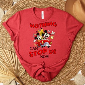 Puede incluir: Camiseta roja con un dise&ntilde;o de Mickey y Minnie Mouse en un coche rojo y el texto "NOTHING CAN STOP US NOW". La camiseta es de cuello redondo y de corte cl&aacute;sico.