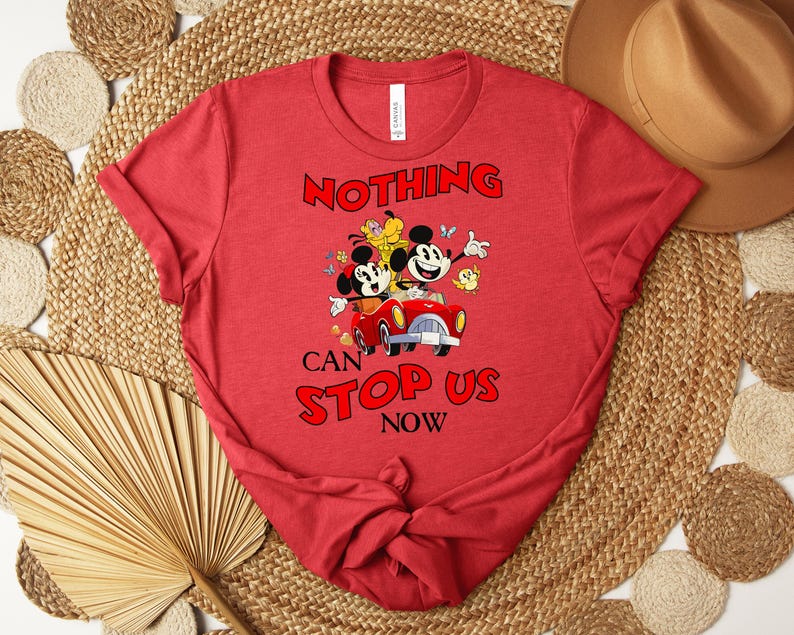 Puede incluir: Camiseta roja con un dise&ntilde;o de Mickey y Minnie Mouse en un coche rojo y el texto "NOTHING CAN STOP US NOW". La camiseta es de cuello redondo y de corte cl&aacute;sico.