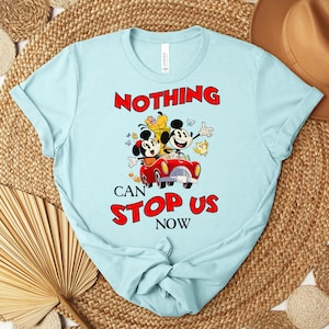 Puede incluir: Camiseta azul claro con un gr&aacute;fico de Mickey y Minnie Mouse en un coche rojo, con las palabras "NOTHING CAN STOP US NOW" en rojo. La camiseta est&aacute; hecha de un material suave.