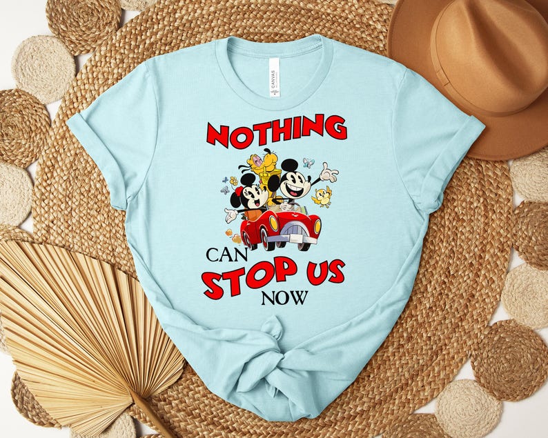 Puede incluir: Camiseta azul claro con un gr&aacute;fico de Mickey y Minnie Mouse en un coche rojo, con las palabras "NOTHING CAN STOP US NOW" en rojo. La camiseta est&aacute; hecha de un material suave.
