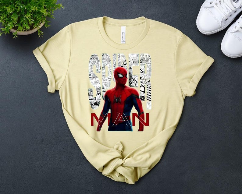 Peut inclure: Un t-shirt &agrave; manches courtes jaune clair avec un graphisme de Spider-Man en costume rouge et bleu. Le mot SPIDER est &eacute;crit en blanc sur un fond de cases de bande dessin&eacute;e en noir et blanc, et le mot MAN est imprim&eacute; en lettres rouges grasses.