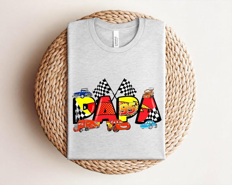 Puede incluir: Camiseta gris claro con la palabra "PAPA" en un dise&ntilde;o colorido con coches de carreras y banderas a cuadros. El dise&ntilde;o incluye el n&uacute;mero "95" e ilustraciones de coches, ideal para un aficionado a los coches.