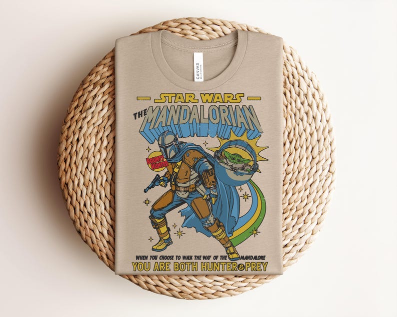 K&ouml;nnte beinhalten: Beiges T-Shirt mit einem farbenfrohen Grafikdesign von The Mandalorian aus Star Wars. Das Design enth&auml;lt den Text "STAR WARS THE MANDALORIAN" und das Zitat "WHEN YOU CHOOSE TO WALK THE WAY OF THE MANDALORE YOU ARE BOTH HUNTER & PREY."