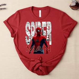 Peut inclure: Un t-shirt rouge &agrave; manches courtes avec un graphisme du personnage Spider-Man en costume rouge et bleu. Le texte SPIDER MAN est imprim&eacute; en grandes lettres blanches remplies de panneaux de bande dessin&eacute;e en noir et blanc sur le torse.