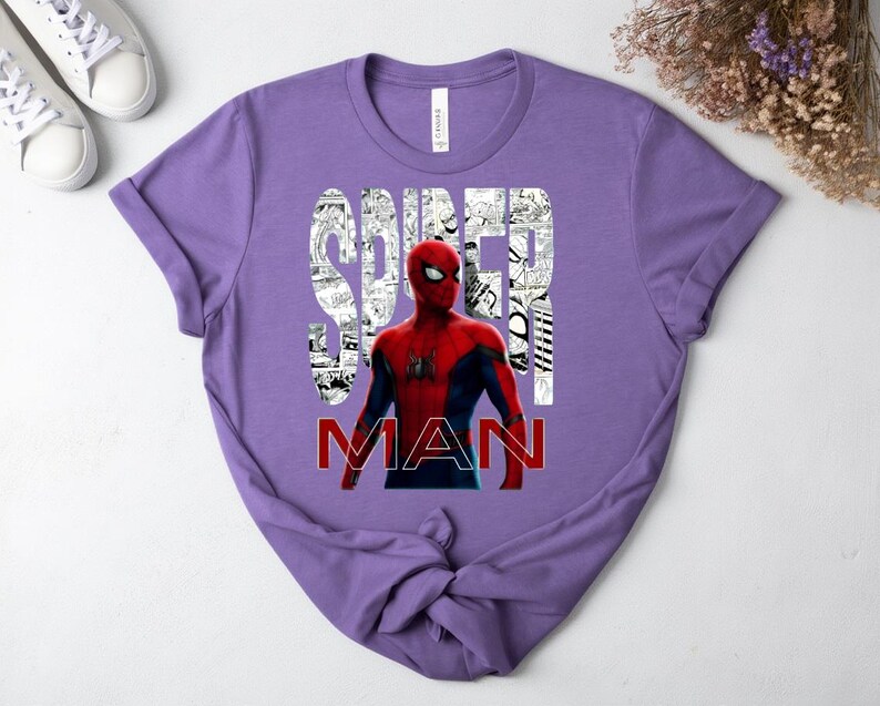 Peut inclure: Un t-shirt &agrave; manches courtes lavande avec un graphique du personnage Spider-Man en costume rouge et bleu. Le mot SPIDER est imprim&eacute; en blanc sur un fond de bande dessin&eacute;e en noir et blanc, et le mot MAN est imprim&eacute; en rouge en dessous.