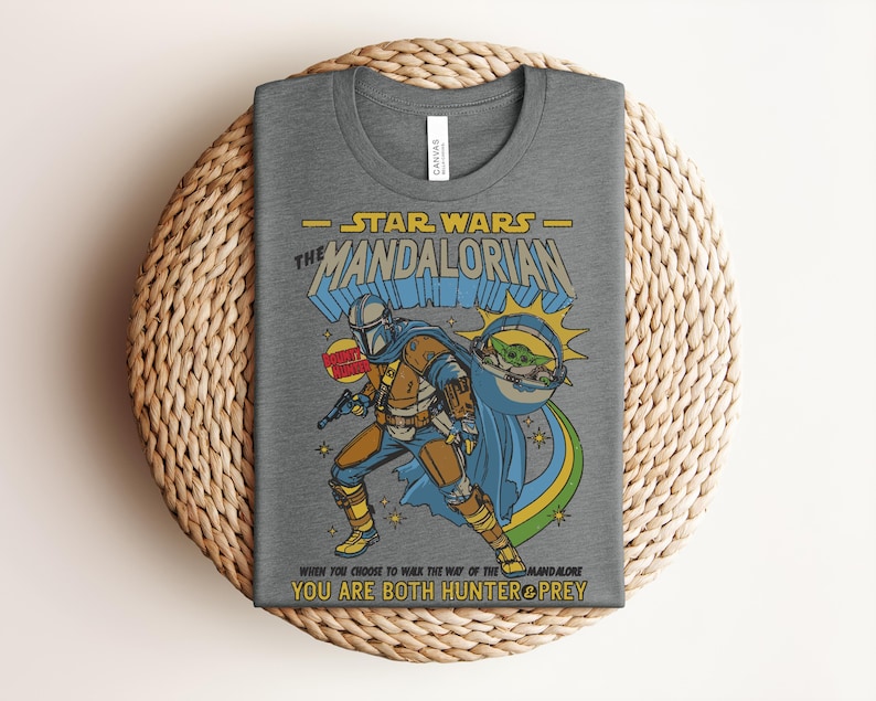 K&ouml;nnte beinhalten: Graues T-Shirt mit einer Grafik von The Mandalorian aus Star Wars. Das Design enth&auml;lt den Text "STAR WARS - THE MANDALORIAN" und das Zitat "WHEN YOU CHOOSE TO WALK THE WAY OF THE MANDALORE YOU ARE BOTH HUNTER & PREY."