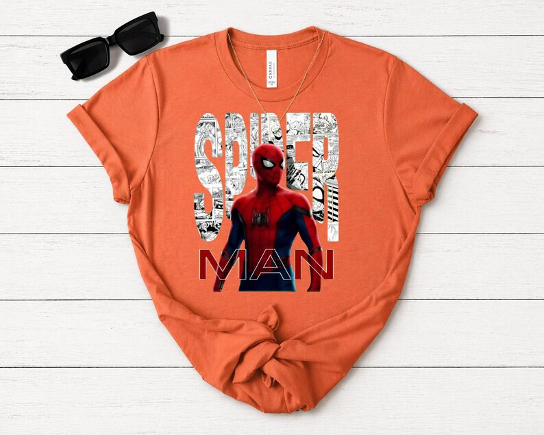 Peut inclure: Un t-shirt orange &agrave; manches courtes avec un motif de Spider-Man en costume rouge et bleu. Le mot SPIDER est imprim&eacute; en grandes lettres blanches remplies de panneaux de bande dessin&eacute;e en noir et blanc, et le mot MAN est imprim&eacute; en rouge.