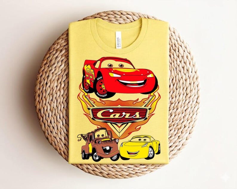 May include: Yellow t-shirt featuring a graphic of Lightning McQueen from the movie Cars, with the word "Cars" in a flame design. The shirt also includes images of Tow Mater and Sally Carrera.
