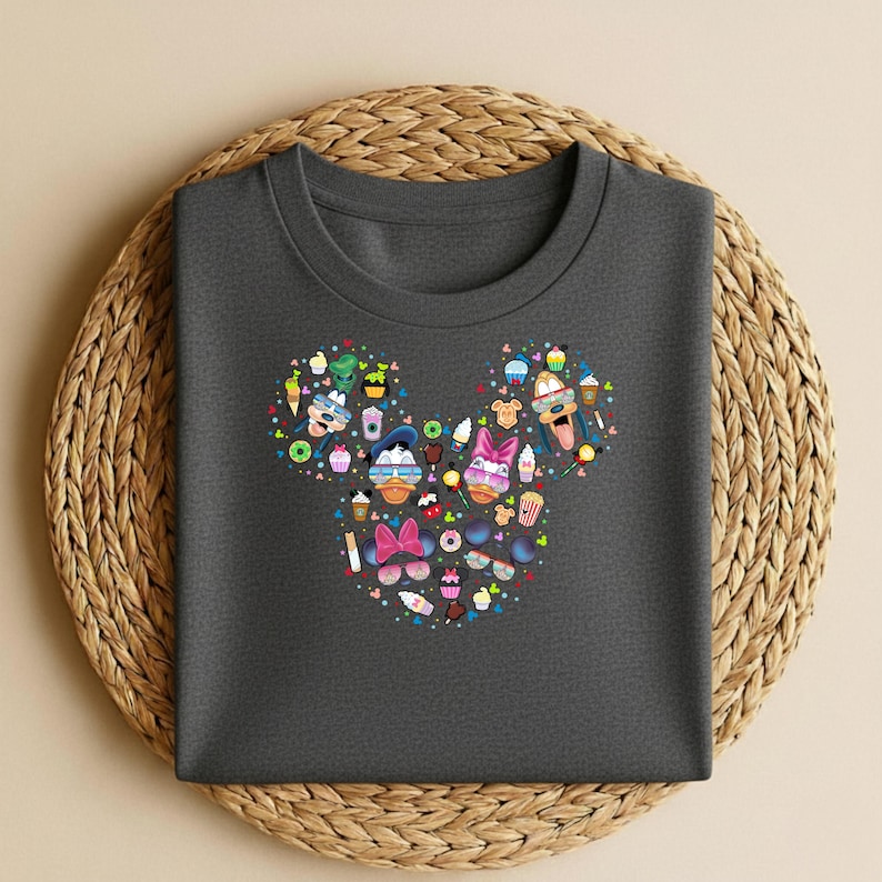 May include: Dark grey t-shirt with a Mickey Mouse head design made up of cartoon characters, sunglasses, ice cream, and other colourful summer-themed graphics. The shirt is on a woven, circular placemat.