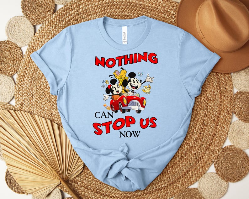 Puede incluir: Camiseta azul claro con un gr&aacute;fico de Mickey y Minnie Mouse en un coche rojo, con el texto "NOTHING CAN STOP US NOW" en rojo. El dise&ntilde;o incluye otros personajes de dibujos animados y es un dise&ntilde;o l&uacute;dico y colorido.