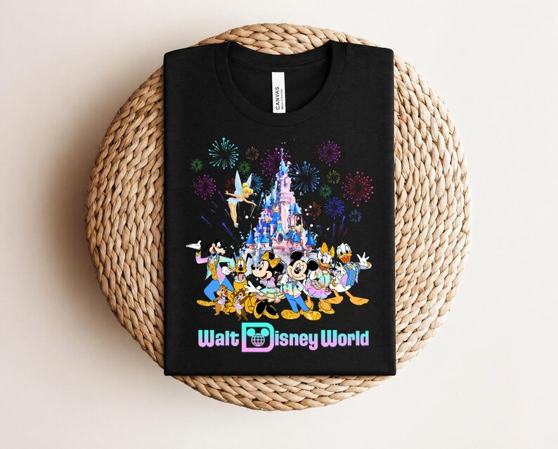 Może przedstawiać: Czarny t-shirt z kolorową grafiką postaci Disneya, zamkiem i fajerwerkami, z napisem "Walt Disney World". Projekt zawiera Myszkę Miki, Minnie, Kaczora Donalda i inne popularne postacie.
