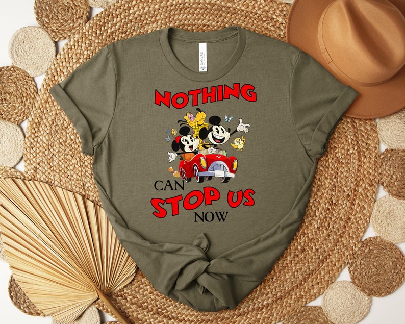 Puede incluir: Camiseta verde oliva con un dise&ntilde;o de Mickey y Minnie Mouse en un coche rojo, con el texto "NOTHING CAN STOP US NOW". El dise&ntilde;o incluye otros personajes de dibujos animados y flores. La camiseta es de material suave.