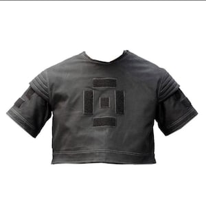 Puede incluir: Una parte superior corta de color gris oscuro con mangas cortas. La parte superior presenta un dise&ntilde;o geom&eacute;trico en la parte delantera hecho de parches negros. Las mangas tienen un dise&ntilde;o en capas con parches negros adicionales. Las costuras blancas delinean los bordes.