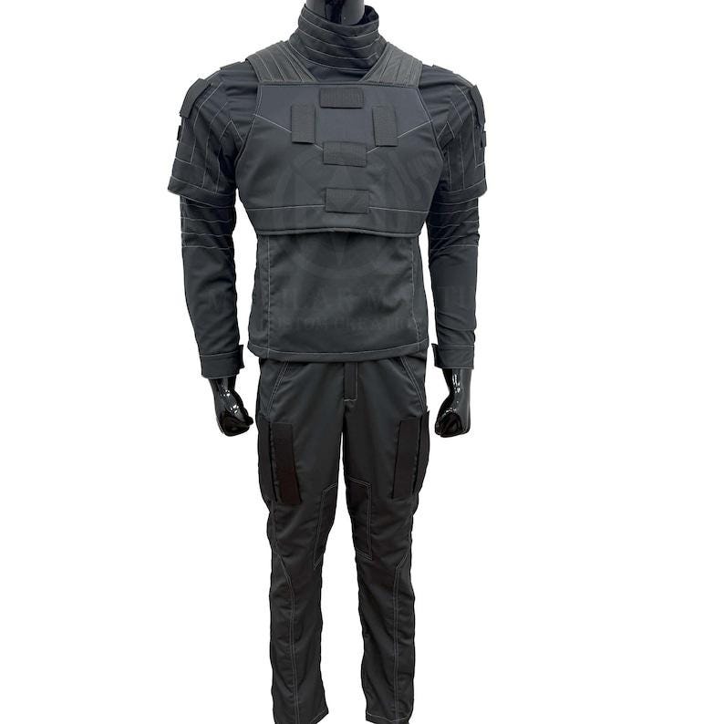 May include: A dark gray tactical outfit displayed on a mannequin. The outfit includes a high-collared jacket with shoulder pads and a chest plate, long-sleeved shirt, and matching pants with cargo pockets. The mannequin wears black gloves.