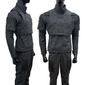 May include: Black tactical outfit, featuring a high-collared jacket with a layered chest piece and matching pants. The jacket has long sleeves and reinforced shoulder details. The pants have multiple pockets. The outfit is displayed on a mannequin.