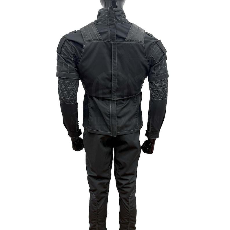 May include: A black tactical jacket and pants set. The jacket features a high collar, reinforced shoulders, and geometric stitching on the sleeves. The pants have a streamlined design. The outfit is made of a matte, durable material.