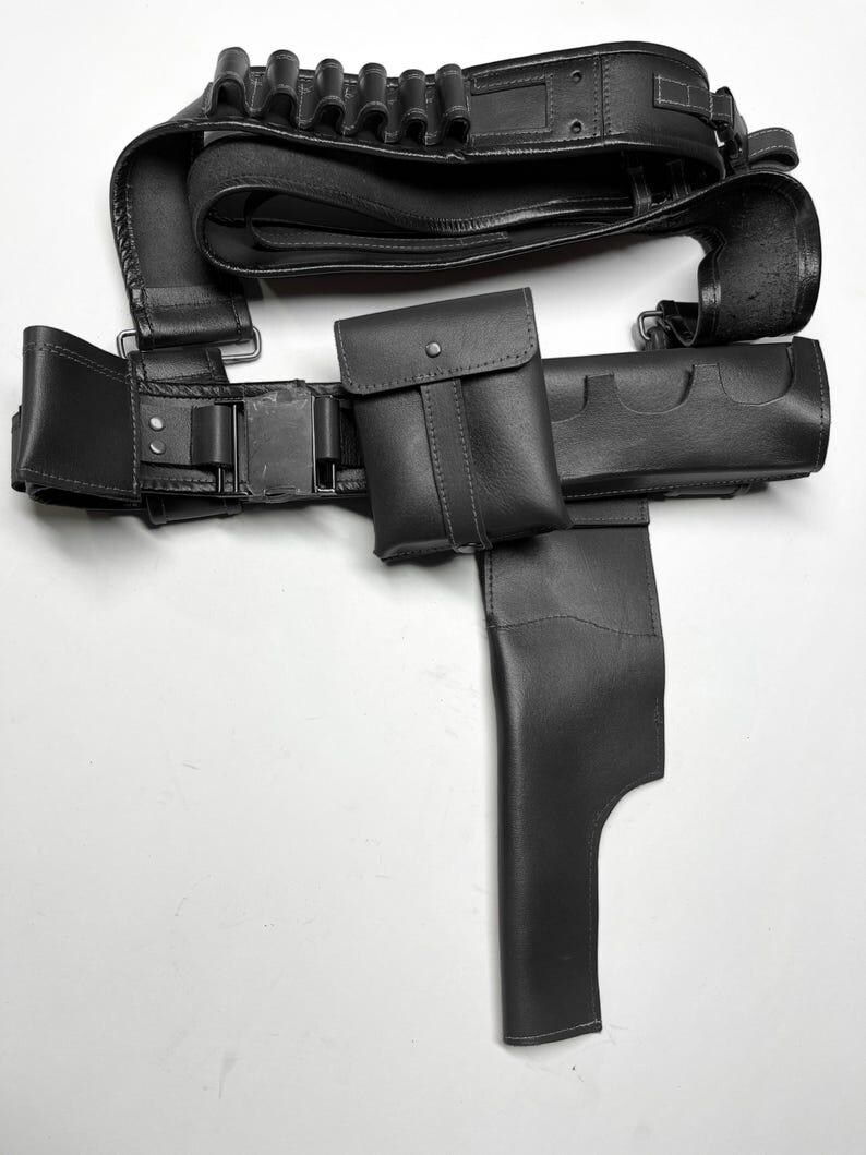 Puede incluir: Un cintur&oacute;n utilitario de cuero negro con m&uacute;ltiples bolsas, una funda y portacartuchos. El cintur&oacute;n presenta un cierre de hebilla y est&aacute; dise&ntilde;ado para transportar varios objetos. El dise&ntilde;o general es elegante y funcional.