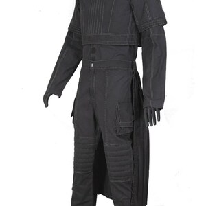 May include: A black costume featuring a long-sleeved top with vertical stitching and a matching cropped overlay. The outfit includes high-waisted pants with cargo pockets and knee padding, and gloves. The costume has a futuristic or sci-fi aesthetic.