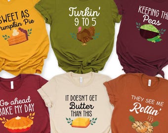 May include: Six short-sleeve t-shirts in mustard, olive, maroon, dark red, cream, and burnt orange. Each shirt features a unique graphic and text: Sweet as Pumpkin Pie, Turkin' 9 to 5, Keeping the Peas, Go ahead BAKE MY DAY, IT DOESN'T GET Butter THAN THIS, and THEY SEE ME Rollin'.