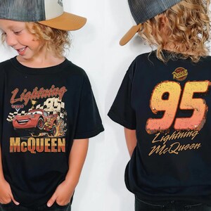 May include: Black t-shirt featuring Lightning McQueen from the Cars movie. The front graphic shows the character with the text "Lightning McQueen" and "95". The back of the shirt displays "95" and "Lightning McQueen".