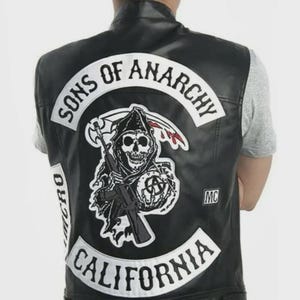 May include: A white ceramic mug with a black handle and the text "But First, Coffee" in a black, handwritten-style font. The mug is on a white surface.