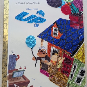 May include: A Little Golden Book featuring a Disney Pixar image from the movie "Up". The cover is embellished with sparkling rhinestones, depicting the house, characters, and balloons. The title and Disney logo are visible.