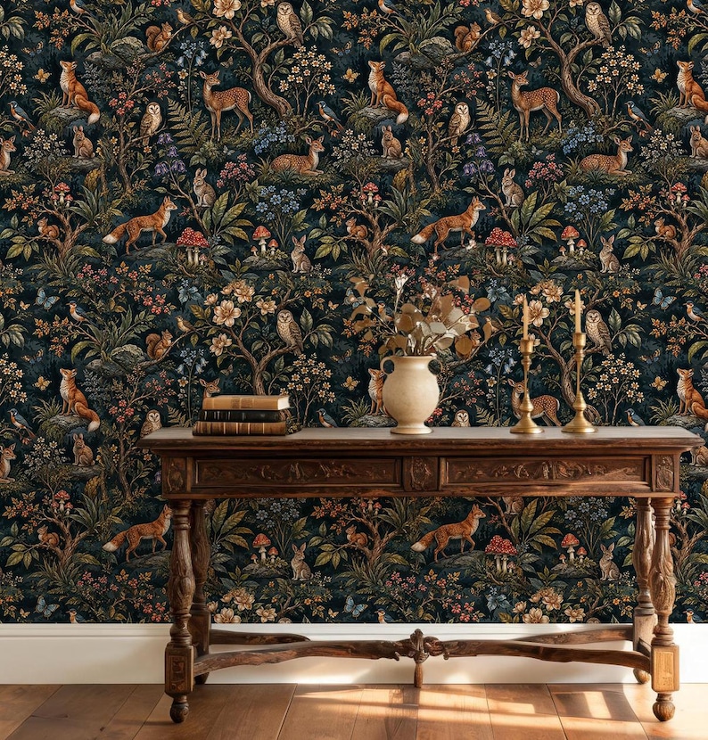 May include: A dark wallpaper featuring a repeating pattern of woodland animals including foxes, deer, owls, rabbits, and squirrels amidst trees, flowers, and mushrooms. A wooden console table stands in front with books and two gold candlesticks.