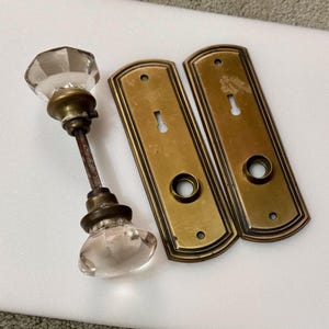 May include: A white ceramic mug with a black handle and the text "But First, Coffee" in a black, handwritten-style font. The mug is on a white surface.