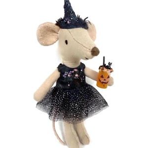May include: A plush mouse doll wearing a dark blue glittery witch hat and a black dress with a sparkly tulle skirt. The mouse has light tan fabric skin and holds a small orange drink cup featuring a jack-o'-lantern face and a black cat topper.