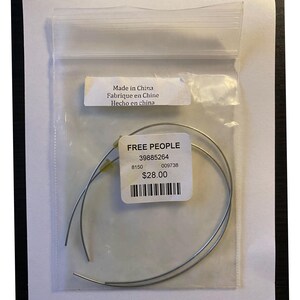 May include: A clear plastic bag containing two silver-colored, curved metal pieces. A white label with the text "FREE PEOPLE" and other details is attached. The bag also has a label that says "Made in China".