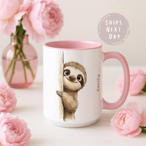 Può includere: Tazza in ceramica bianca con manico e interno rosa. La tazza presenta un'illustrazione di un bradipo dei cartoni animati che sbuca da dietro un albero. Il nome "Emily" è stampato sul lato. Fiori rosa e un vaso sullo sfondo.