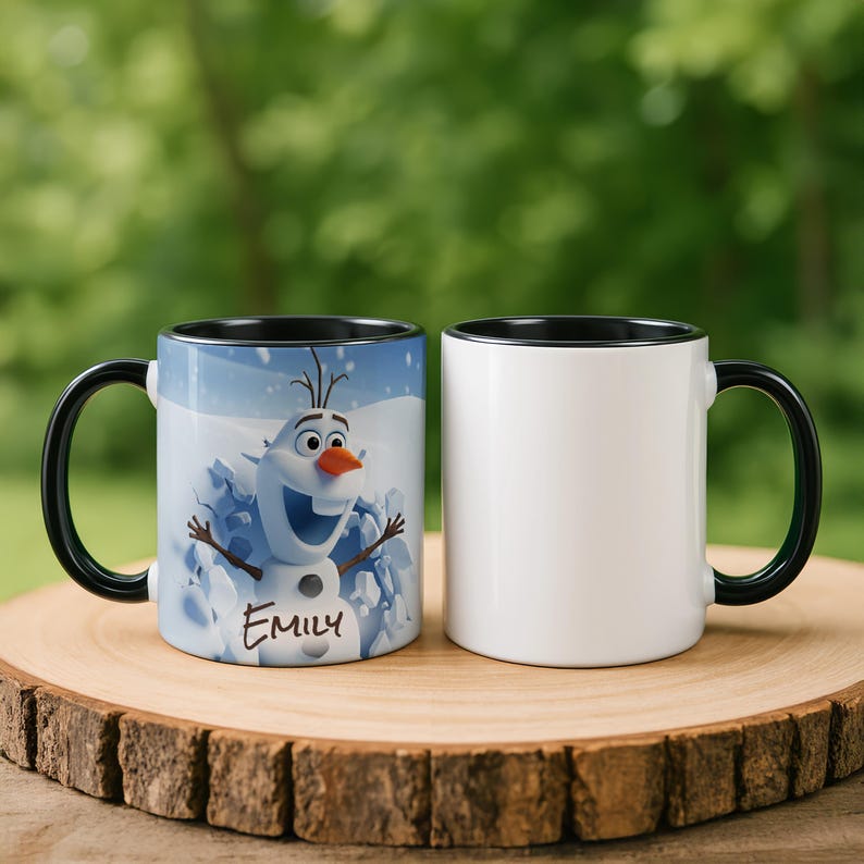 May include: Two ceramic mugs with black handles and rims. One mug features a smiling Olaf the snowman from Frozen, with the name "Emily" below. The other mug is plain white. Both mugs sit on a wooden surface.