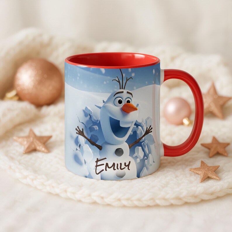 May include: A white ceramic mug with a red interior and handle. The mug features a cartoon image of Olaf the snowman from Frozen, emerging from ice. The name "Emily" is printed on the front. Decorative ornaments and stars surround the mug.