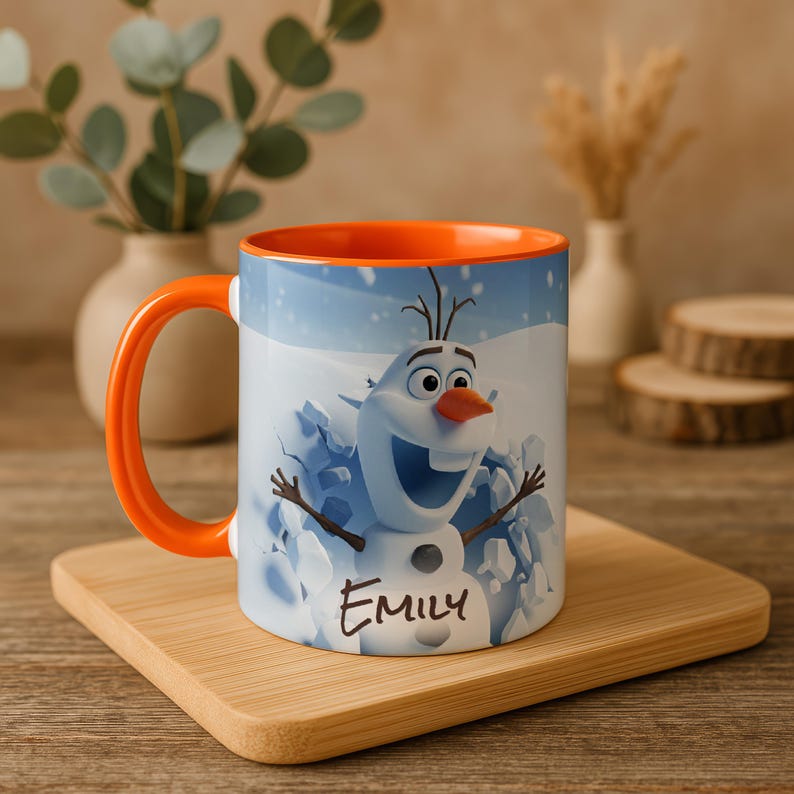 May include: A white ceramic mug with an orange handle and interior. The mug features a cartoon image of Olaf the snowman from Frozen, emerging from a snowy background. The name "Emily" is written in black script below the image.