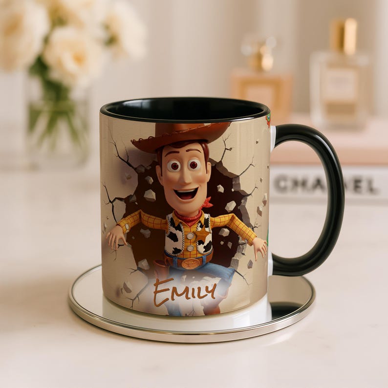 May include: A ceramic mug with a black handle and interior, decorated with a colourful image of Woody from Toy Story. The name "Emily" is written on the front. The mug is on a small, round, silver-coloured coaster. The mug's design shows Woody breaking through a wall.